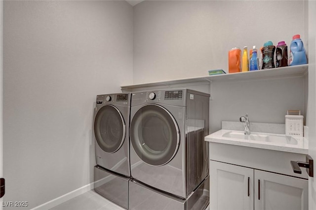 clothes washing area featuring light tile patterned floors, a sink, baseboards, washer and dryer, and cabinet space