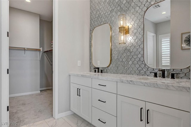 bathroom with marble finish floor, baseboards, backsplash, and a sink