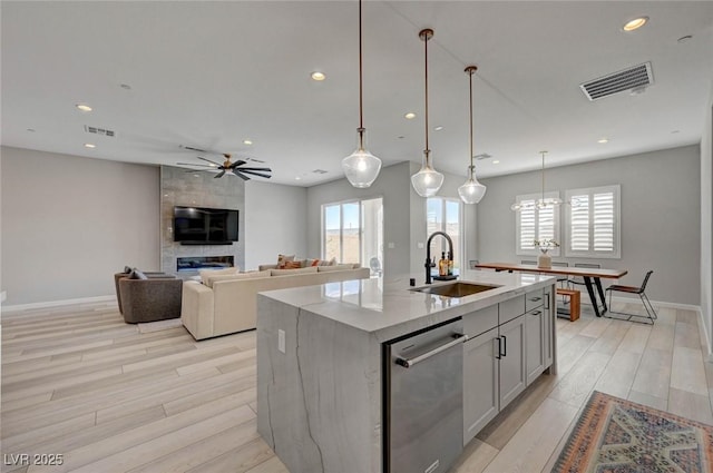 kitchen with dishwasher, light wood finished floors, a sink, and visible vents