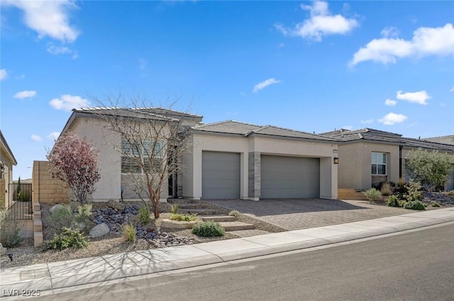 view of front of house featuring a garage, decorative driveway, and stucco siding