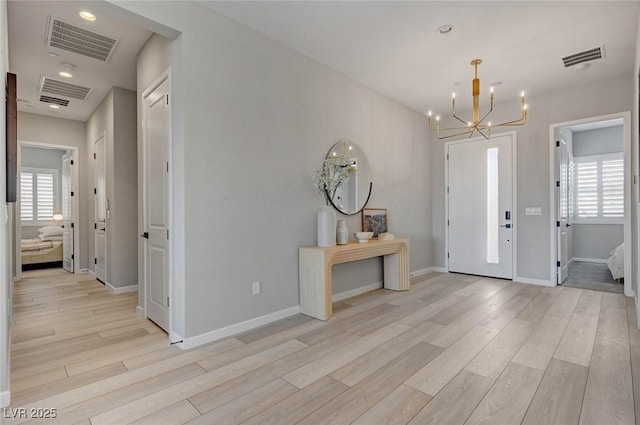 foyer entrance with a wealth of natural light, visible vents, and light wood finished floors