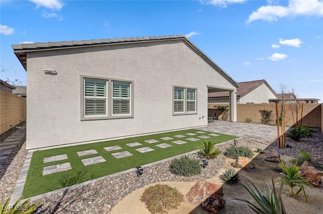 rear view of property with a fenced backyard, a patio, and stucco siding