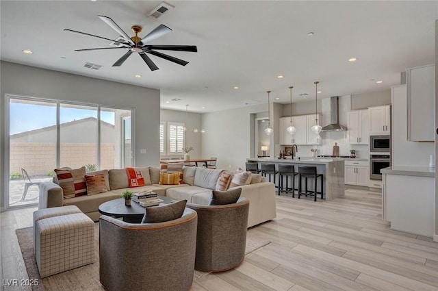 living room with light wood finished floors, visible vents, and recessed lighting