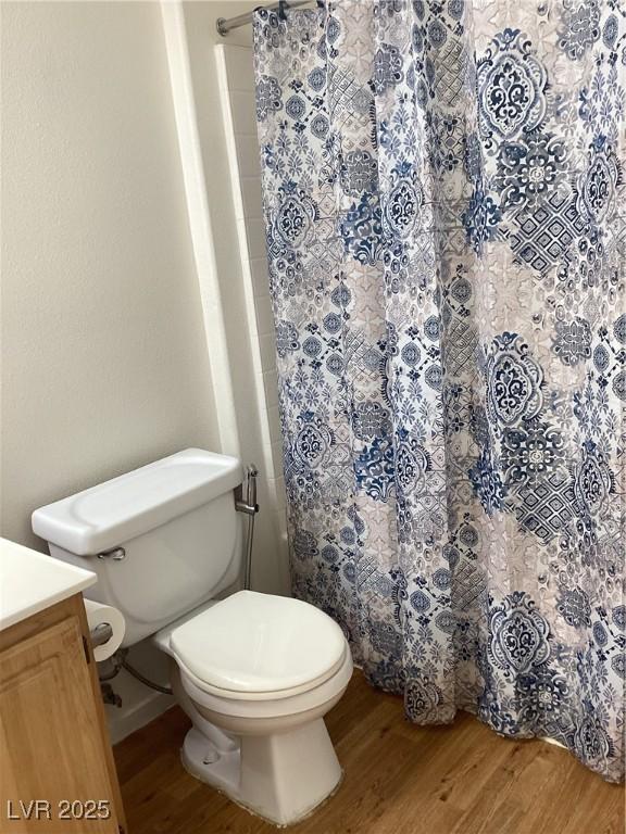 bathroom featuring toilet, a shower with curtain, wood finished floors, and vanity