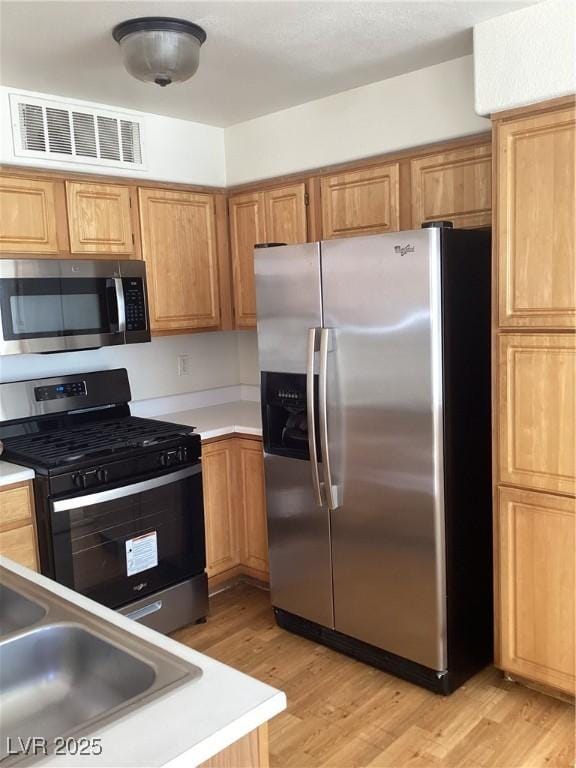 kitchen featuring light wood-style floors, visible vents, appliances with stainless steel finishes, and light countertops