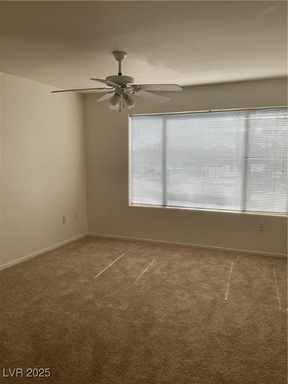 empty room featuring baseboards, a ceiling fan, and carpet flooring