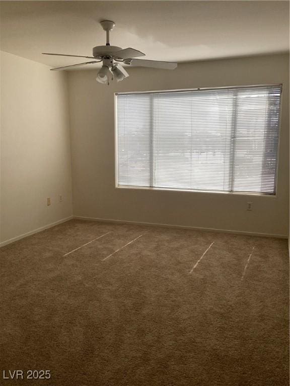 carpeted empty room with a healthy amount of sunlight, ceiling fan, and baseboards