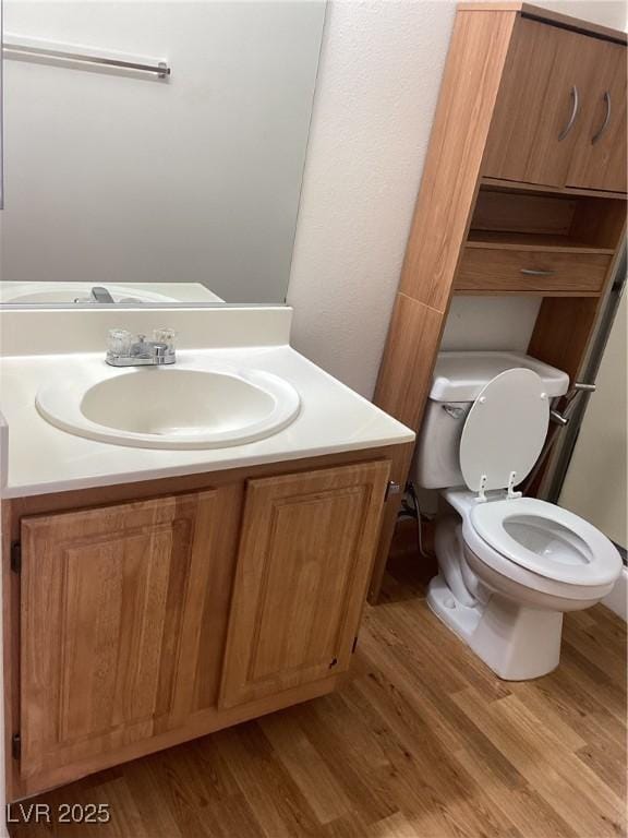 bathroom with vanity, toilet, and wood finished floors