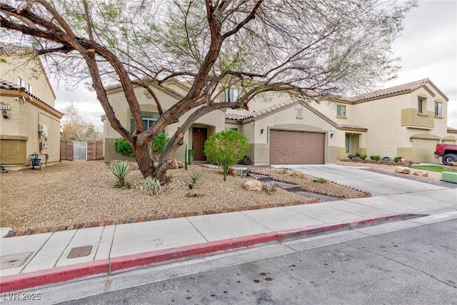 mediterranean / spanish home with a tile roof, stucco siding, concrete driveway, an attached garage, and a gate