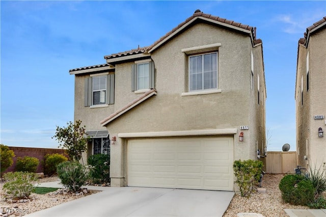 view of front of house with fence, a tiled roof, concrete driveway, stucco siding, and a garage