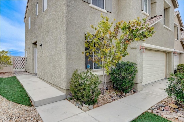 view of side of home featuring a garage and stucco siding