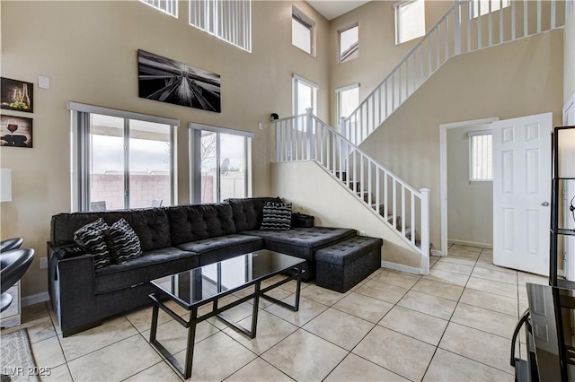 living room with stairs, light tile patterned floors, baseboards, and a towering ceiling