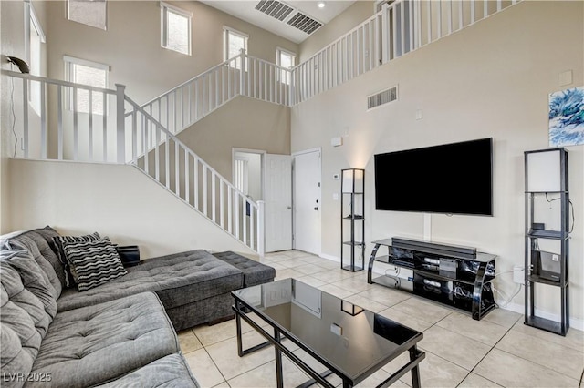 living area with visible vents, plenty of natural light, light tile patterned flooring, and stairway