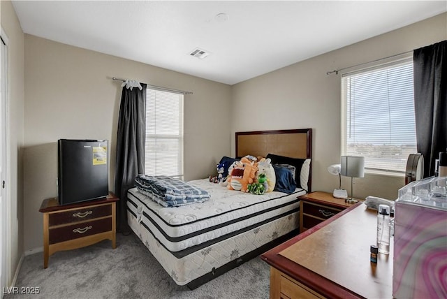 bedroom featuring visible vents, multiple windows, and light colored carpet