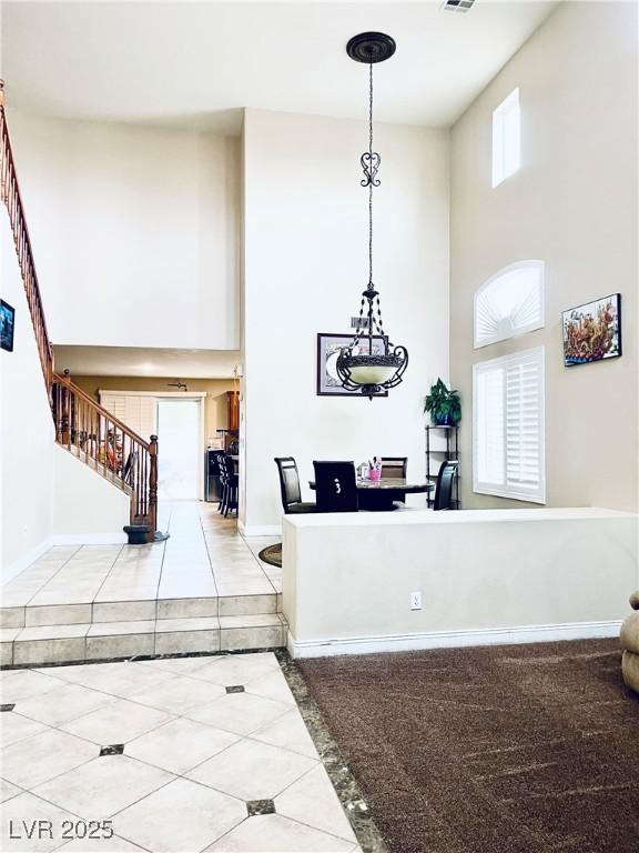 interior space featuring decorative light fixtures, a towering ceiling, baseboards, and tile patterned floors