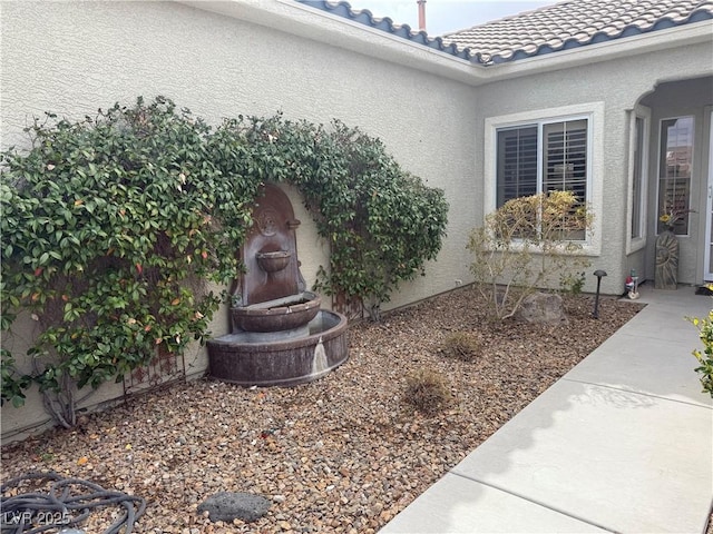 exterior details featuring a tile roof and stucco siding