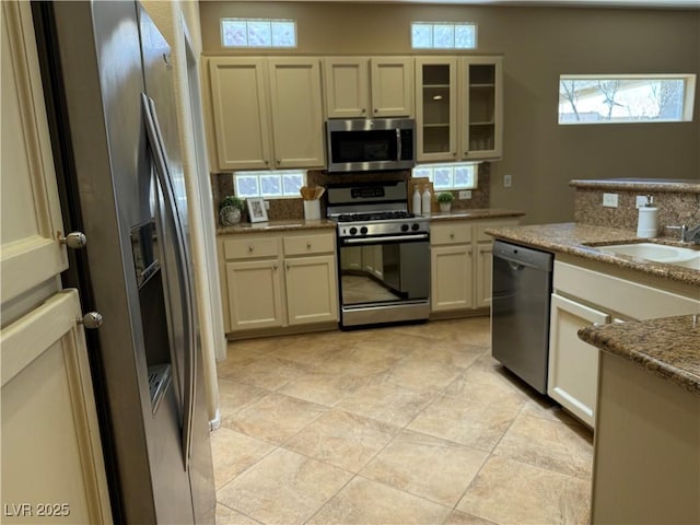 2715 Riceville Dr, Henderson, NV 89052 - kitchen with appliances with stainless steel finishes, a sink, glass insert cabinets, light stone counters, and decorative backsplash