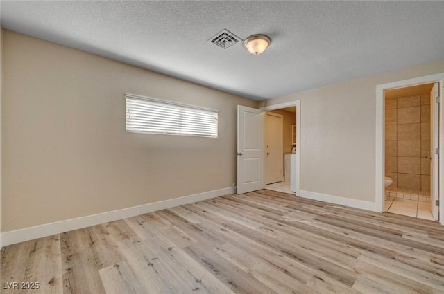 spare room with baseboards, a textured ceiling, visible vents, and wood finished floors