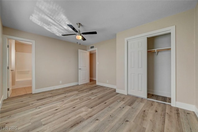 unfurnished bedroom with a closet, wood finished floors, visible vents, and baseboards