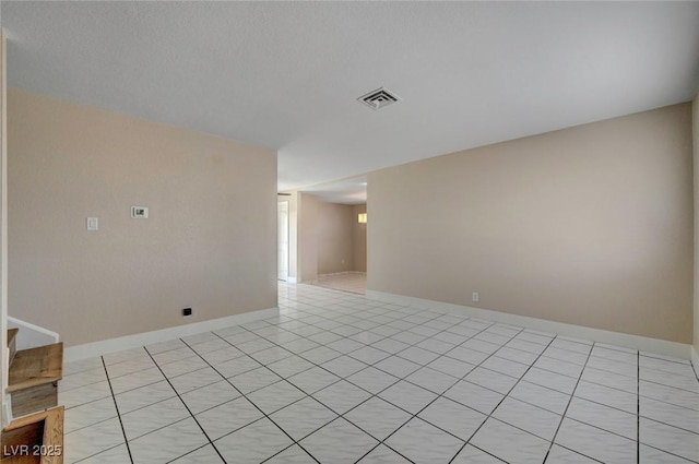 empty room with light tile patterned flooring, visible vents, and baseboards