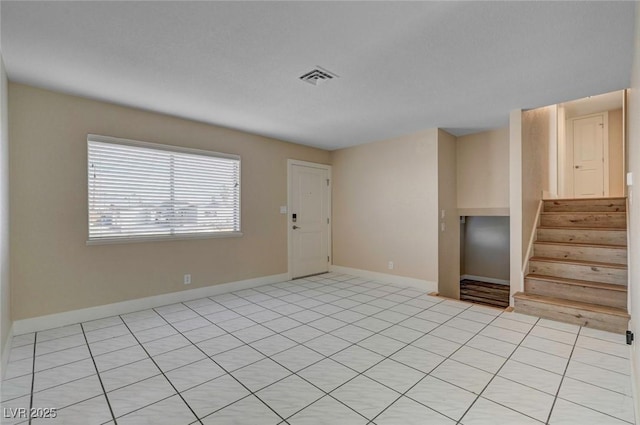 empty room featuring visible vents, stairway, and baseboards