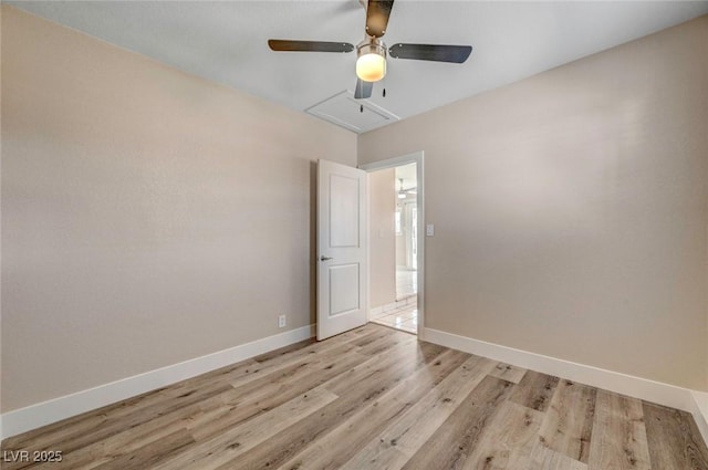 empty room featuring light wood finished floors, baseboards, and a ceiling fan