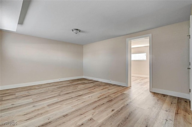 spare room featuring light wood finished floors and baseboards