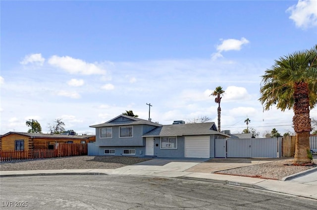 tri-level home with a gate, fence, and driveway