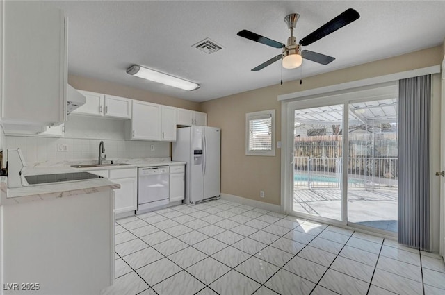 kitchen featuring white appliances, a sink, light countertops, white cabinetry, and backsplash