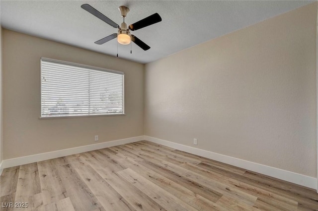 spare room featuring light wood-type flooring, ceiling fan, and baseboards