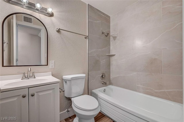 bathroom featuring a textured wall, shower / tub combination, toilet, visible vents, and vanity