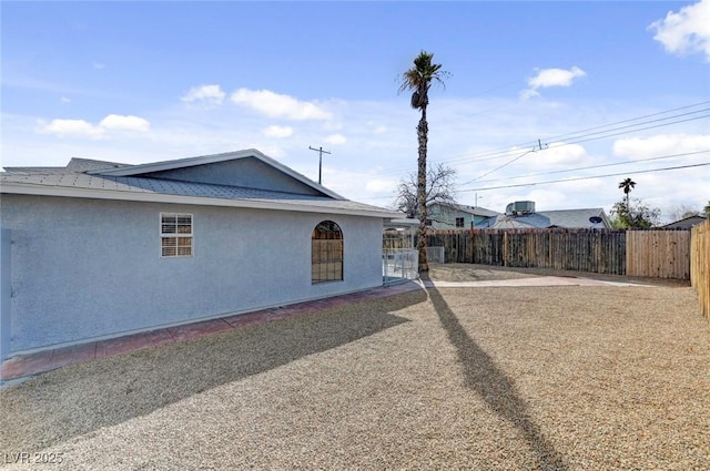 view of side of property featuring fence and stucco siding