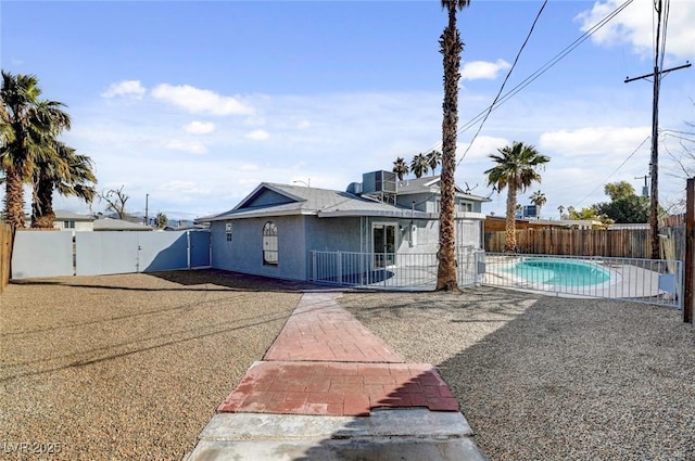 back of house with stucco siding, a fenced backyard, a fenced in pool, and a patio