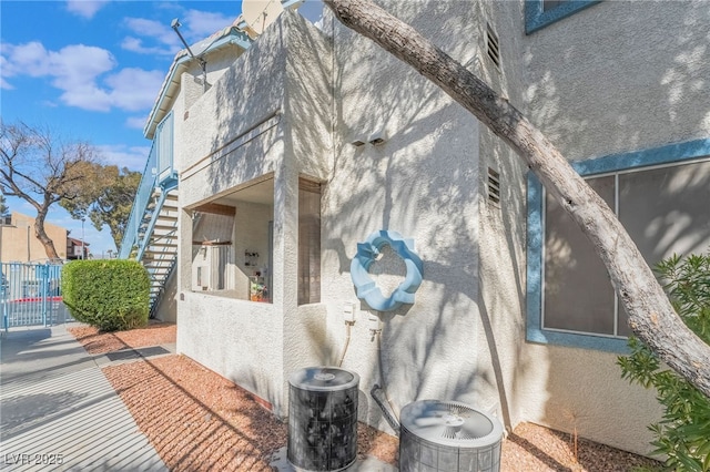 view of side of home featuring fence and stucco siding