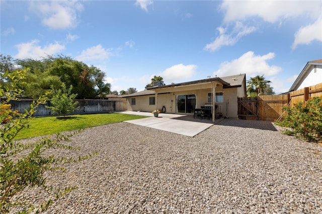 rear view of house with a fenced backyard, a yard, a gate, stucco siding, and a patio area