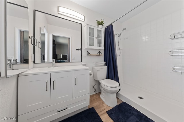 bathroom featuring a stall shower, vanity, toilet, and wood finished floors