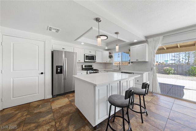 kitchen featuring a tray ceiling, stainless steel appliances, light countertops, visible vents, and a sink