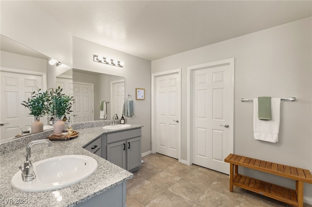 bathroom featuring a sink, baseboards, and double vanity