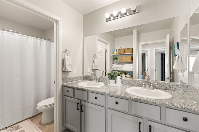 full bathroom with double vanity, toilet, a sink, and tile patterned floors