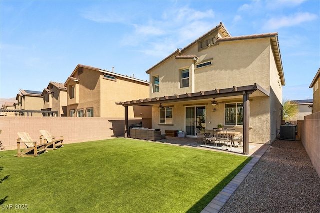 rear view of property featuring stucco siding, a lawn, ceiling fan, cooling unit, and a fenced backyard