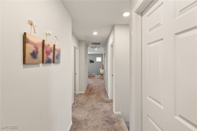 hall with attic access, recessed lighting, light carpet, and baseboards