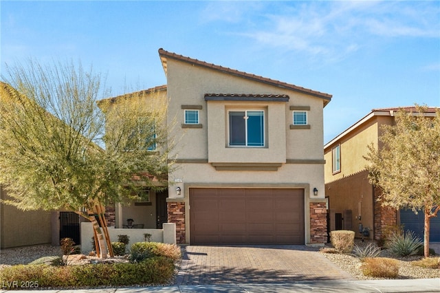 view of front of home featuring decorative driveway, stone siding, and stucco siding