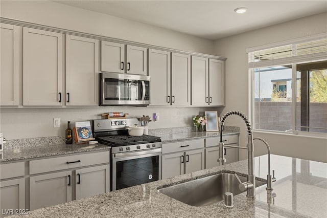 kitchen featuring light stone countertops, stainless steel appliances, a sink, and recessed lighting