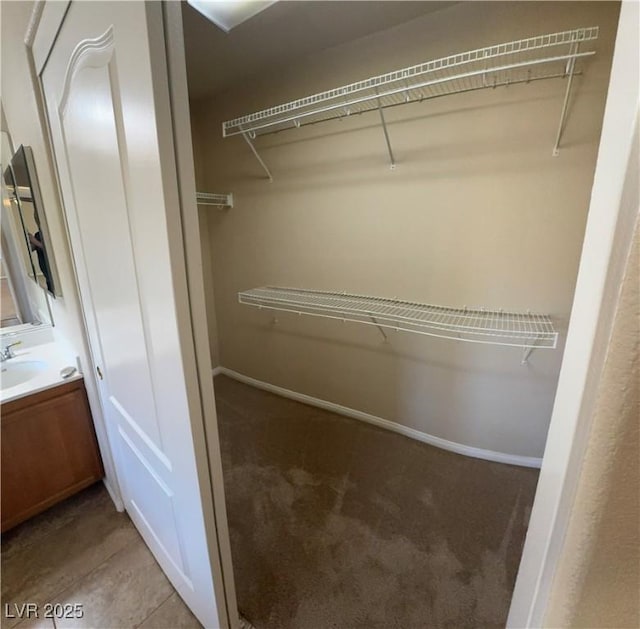 spacious closet with light carpet, light tile patterned flooring, and a sink