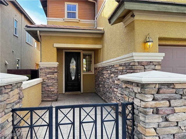 property entrance with a garage, stone siding, fence, and stucco siding