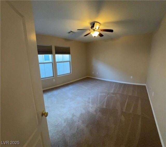 carpeted empty room with baseboards, visible vents, and a ceiling fan