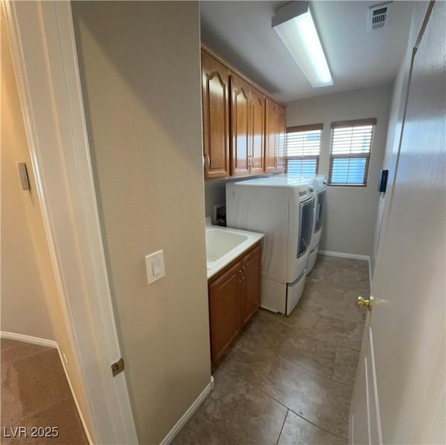 clothes washing area with cabinet space, baseboards, visible vents, washer and clothes dryer, and a sink