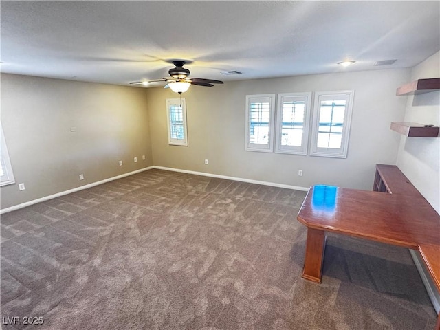 unfurnished office featuring visible vents, baseboards, dark colored carpet, and a ceiling fan