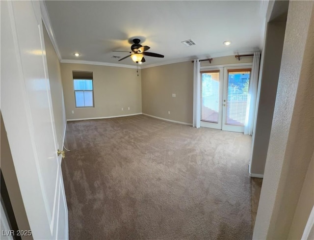 carpeted empty room with french doors, crown molding, visible vents, a ceiling fan, and baseboards