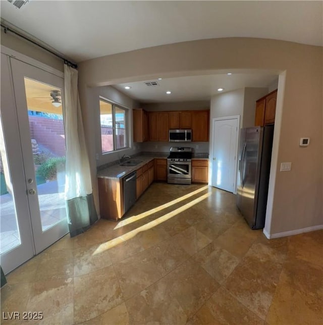 kitchen with baseboards, brown cabinets, stainless steel appliances, a sink, and recessed lighting